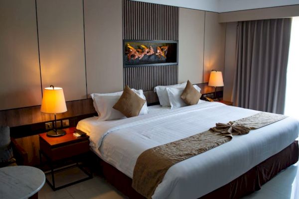 This image shows a well-decorated hotel room with a neatly made bed, bedside tables with lamps, and a modern wall design.