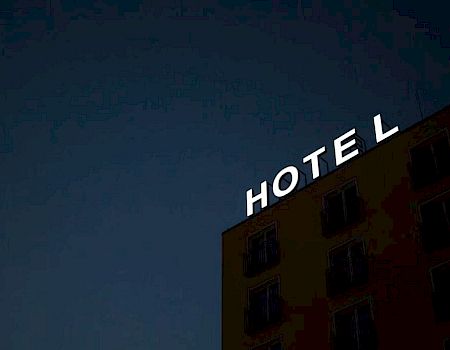 A hotel building with illuminated letters spelling “HOTEL” atop it, missing the letter 