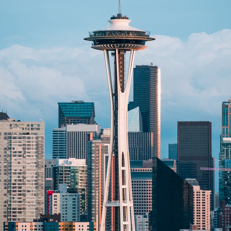 The image shows the Space Needle, a prominent observation tower in Seattle, with a backdrop of various buildings and skyscrapers in the city.