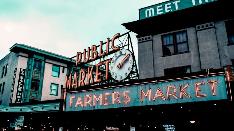 The image shows a public market with a neon 